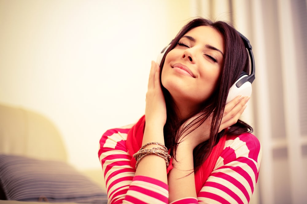A woman is listening to music attentively on a couch.