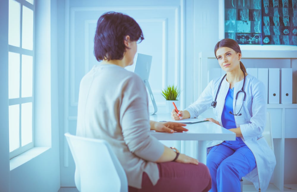 A doctor is going in circles while talking to a patient in a doctor's office.