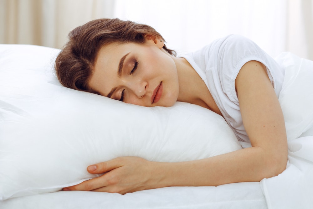 A woman experiencing less oxygen while sleeping on a white pillow.
