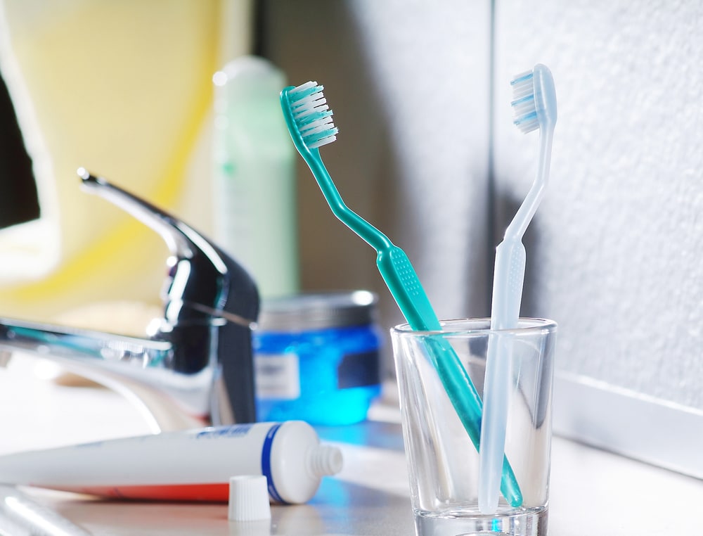 A general dentist's supplies - toothbrush, toothpaste, and a glass of water - on a counter.
