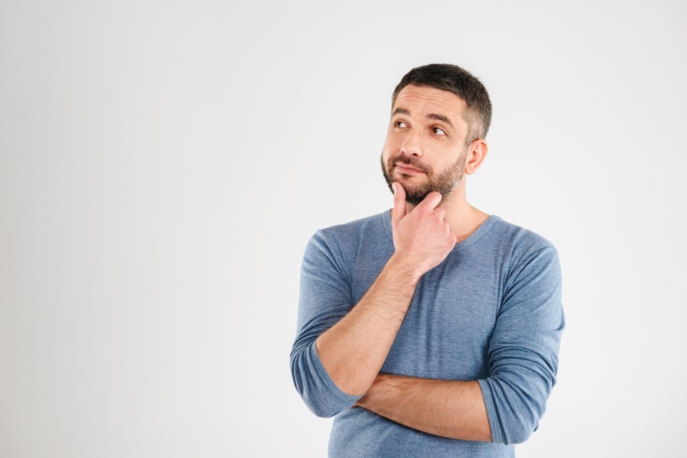 A man with his hand on his chin thinking about dental options.