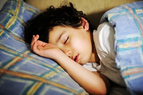 A young boy sleeping in a bed.