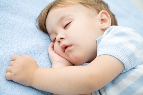 A baby sleeping on a blue blanket. (No keywords added)
