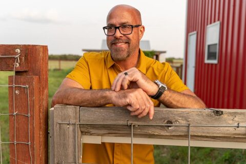 a man standing near a farm smiling