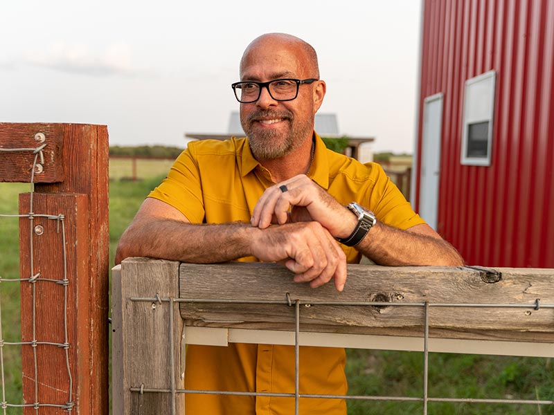 a man standing near a farm smiling