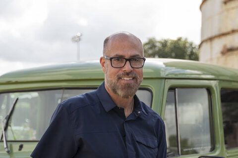 a man smiling standing near a car