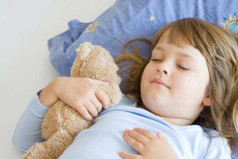 a child sleeping with a teddy bear