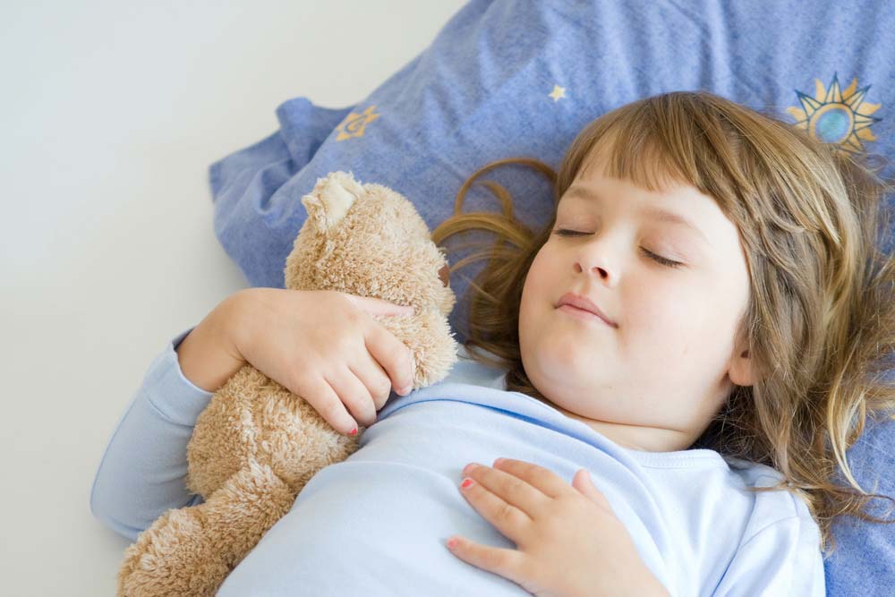 a child sleeping with a teddy bear