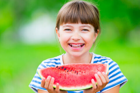 a little girl eating watermelon and smiling