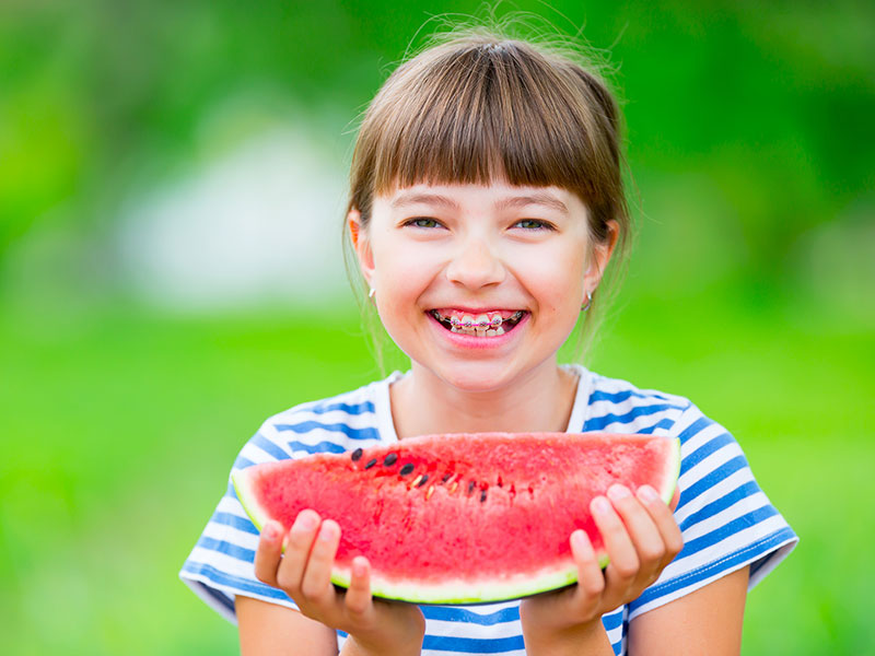 a little girl eating watermelon and smiling